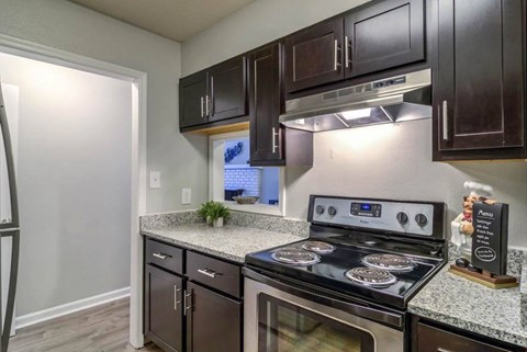 A kitchen with a stove top oven and a microwave. at The Onyx Hoover Apartments, Hoover, 35216